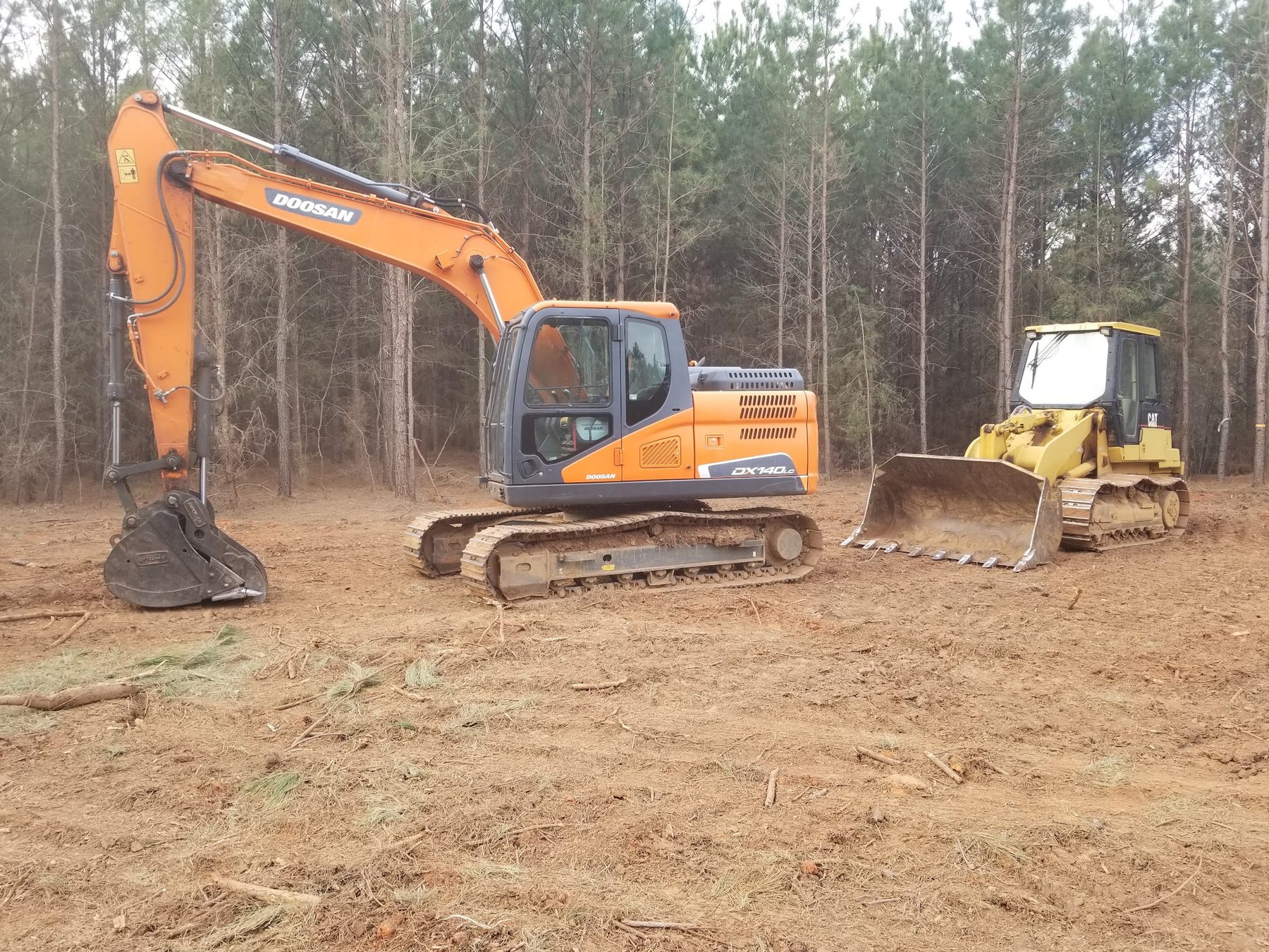 Excavator and dozer clearing and grading a residential lot